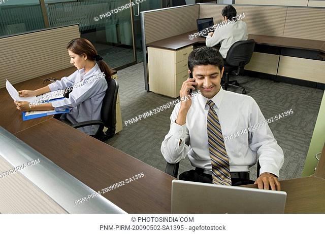 Businessman using a mobile phone with his colleagues working behind him
