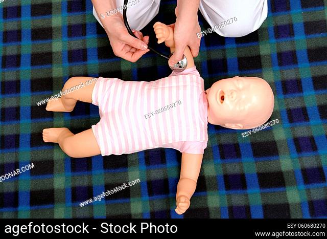 Infant first aid series - First aid instructor showing how to check pulse on infant dummy using stethoscope