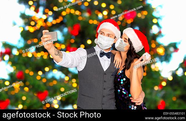 couple in medical masks taking selfie on christmas