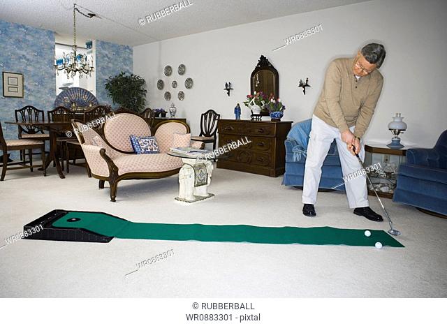 Senior man playing golf in the living room