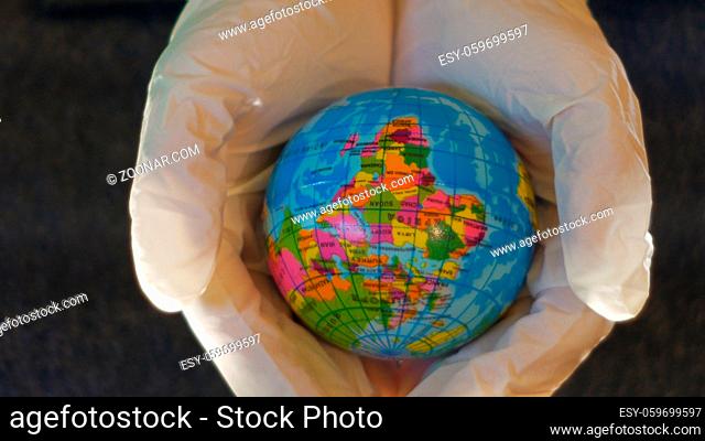 teenage girl holds a globe in hands with white gloves, above it appears a sheet of bubble wrap, ideal footage to represent ecology themes, concept