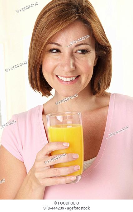 A smiling woman holding a glass of orange juice
