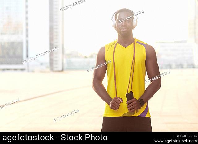 Closeup portrait of handsome sporty afro man holding jump rope. Outdoor shot