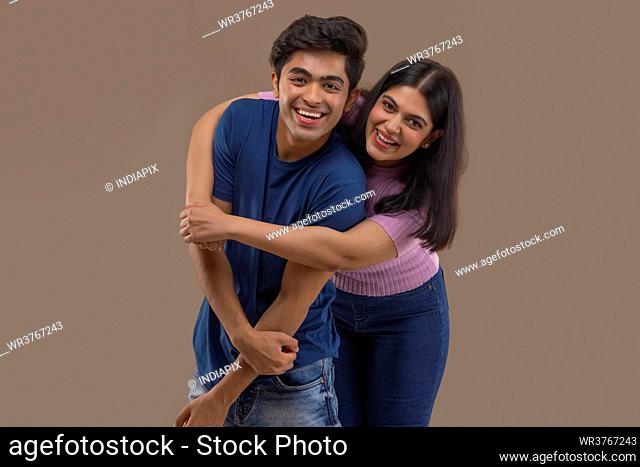 A HAPPY BROTHER AND SISTER POSING TOGETHER IN FRONT OF CAMERA
