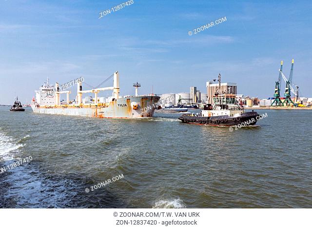 ANTWERP, BELGIUM - AUG 13: Tugboat with cargo ship on August 13, 2015 in the harbor of Antwerp, Belgium
