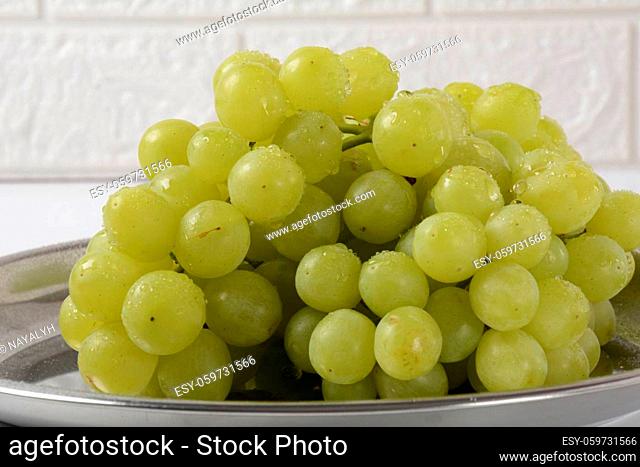 Bunch of green grapes in a silver tray, fruits of autumn, on white background