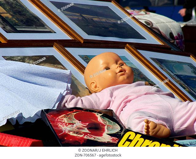 Blick auf einen Stand auf dem Flohmarkt - mit Puppe, Büchern, Kleidern etc