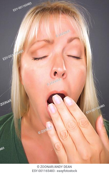 Yawning Blond Woman Against a Grey Background