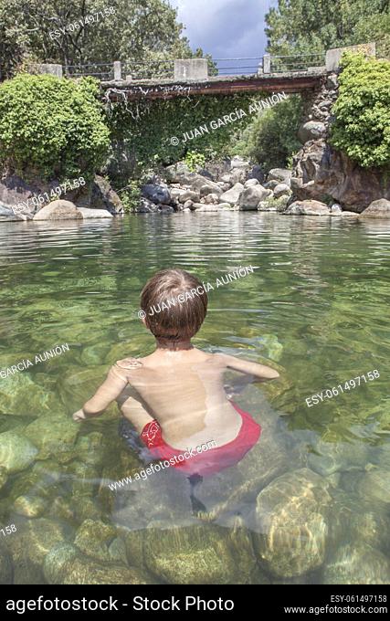 Child boy at La Maquina Natural swimming pool. Crystal-clear waters spot in the heart of La Vera County, Caceres, Extremadura, Spain
