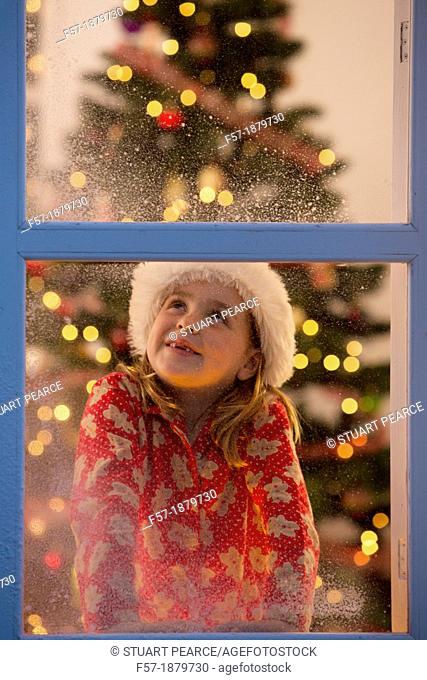 Young girl looking out of the window waiting for Santa to arrive