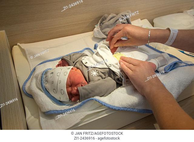 hands changing napkin of new born baby in hospital