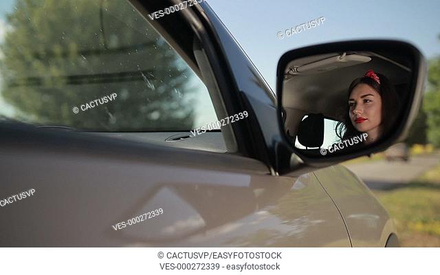 Reflection of cute girl in rearview mirror of car