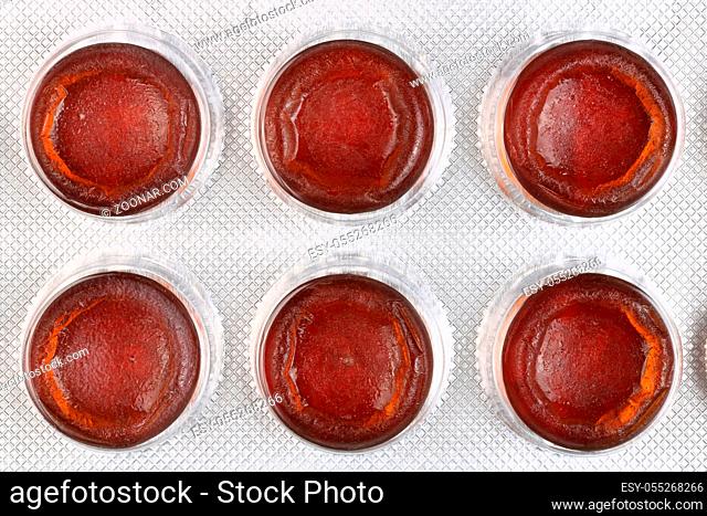 Six red tablets to increase hemoglobin in the blood are packed in white plastic. Top view studio macro shot