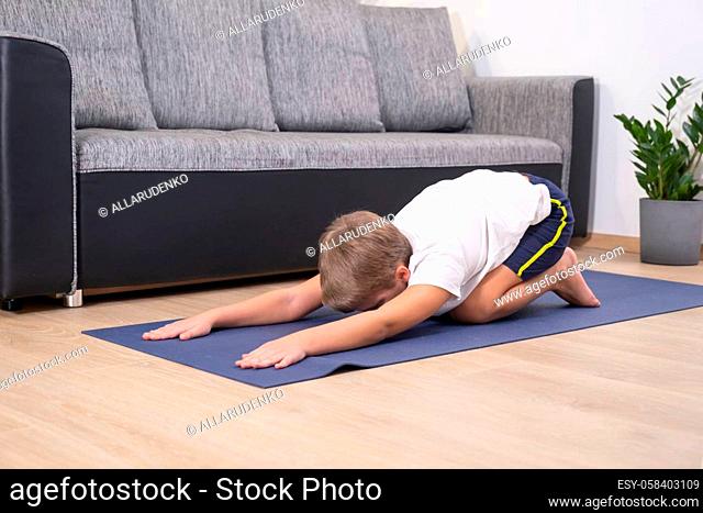 Blond boy goes in for sports on yoga mat. Child physical activity. Sport healhty lifestyle active leisure at home during COVID-19 quarantine