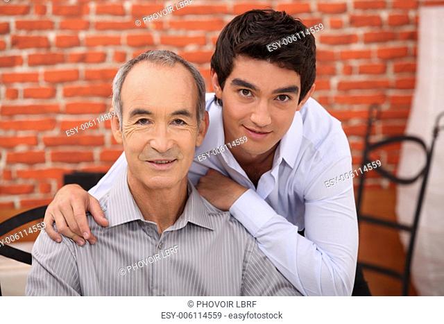a teenager and his grandfather posing in a restaurant