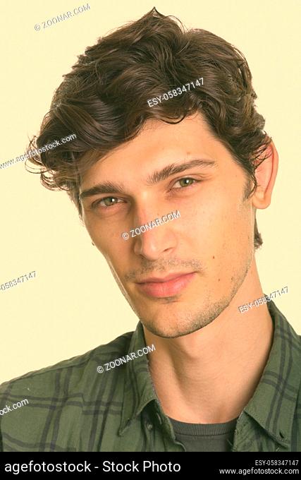 Studio shot of young handsome Hispanic hipster man against white background