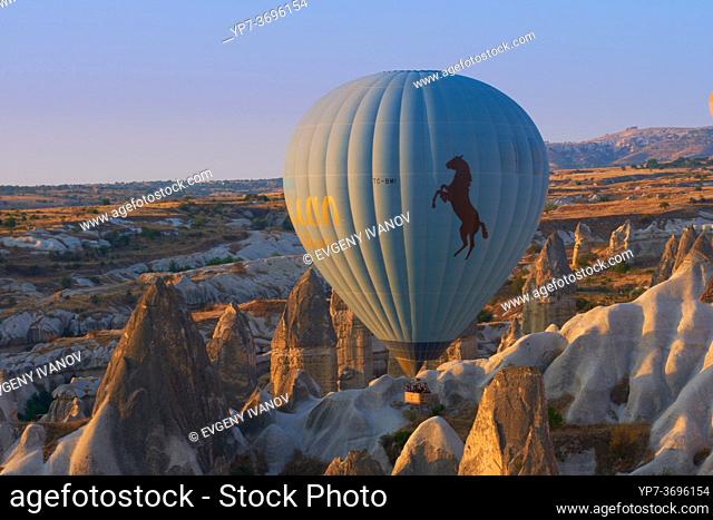 Hot air balloon flying between tuff rocks over Goreme valley in Cappadocia, Turkey