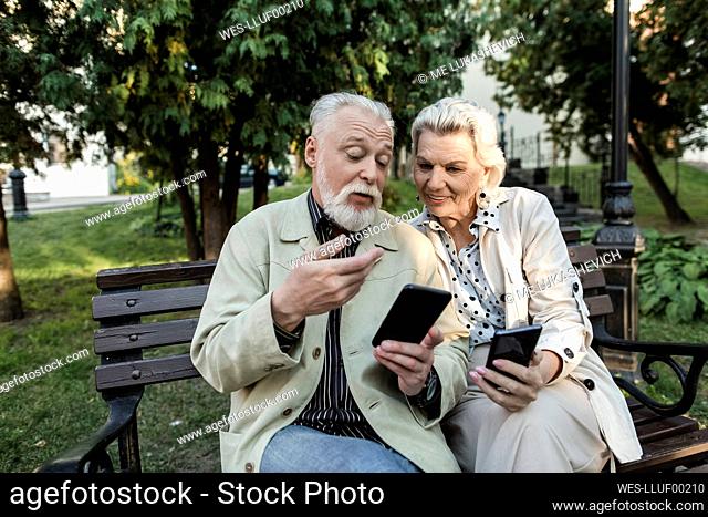 Couple using smart phones while sitting on bench