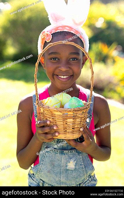Portrait of african american girl holding basket while easter egg hunting
