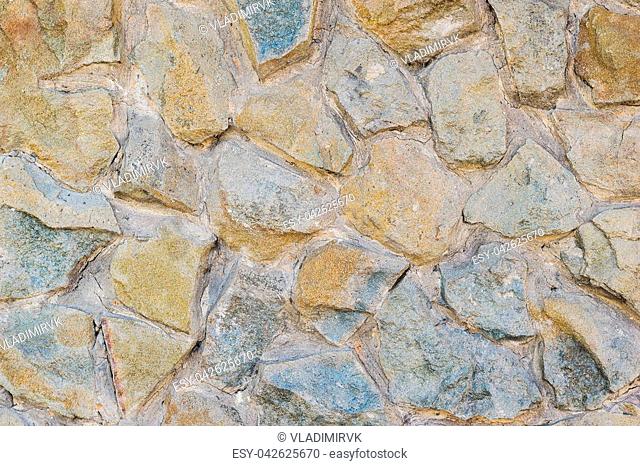 A fragment of an artificially made wall of stone and binder solution. Background of stone wall