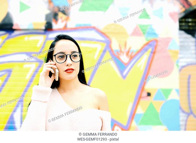 Portrait of woman on the phone in front of graffiti wall
