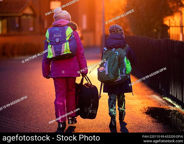 10 January 2022, Lower Saxony, Laatzen: Two schoolchildren walk to their elementary school in the Hannover region early in the morning