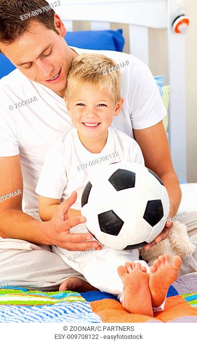 Smiling little boy and his father playing with a soccer ball