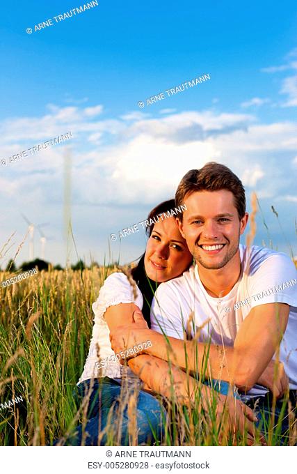 Glückliches Paar sitzt auf einer Wiese oder Kornfeld