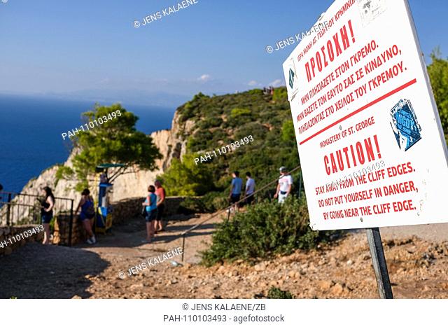 01.10.2018, Greece, Zakynthos: A warning sign ""Caution!"" stands on the steep coast of Navagio Bay on the Greek island of Zakynthos