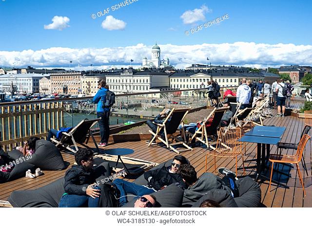 Helsinki, Finland, Europe - People sunbathe on the rooftop of the Allas Sea Pool with the central market square, the Presidential Palace and the Helsinki...