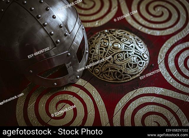 Soldier Viking helmet with chain mail of iron on red shield of wood and golden triskel