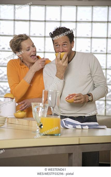 Mature couple in kitchen, Man eating grapefruit