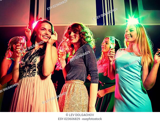 party, holidays, celebration, nightlife and people concept - smiling friends with glasses of champagne dancing in club