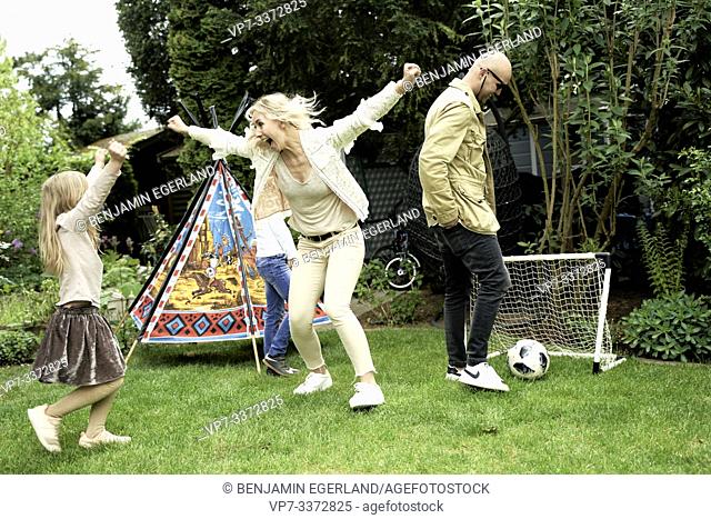 Family playing soccer in garden