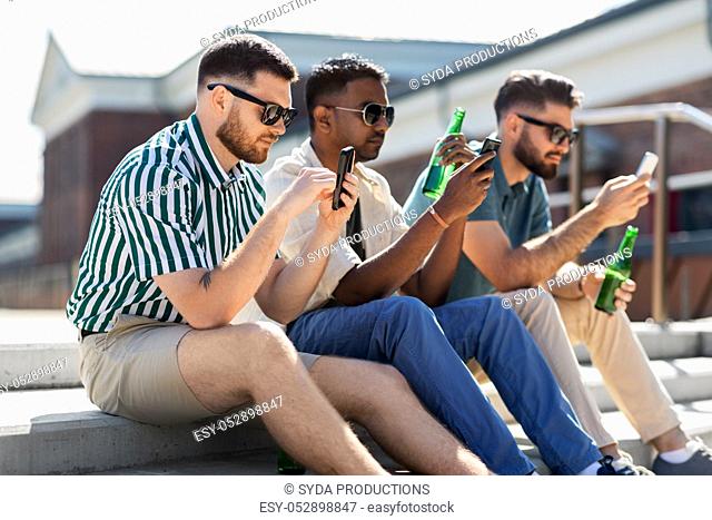 men with smartphones drinking beer on street