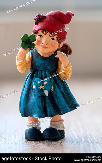 Close-up of a garden gnome holding a lucky clover on a wooden table