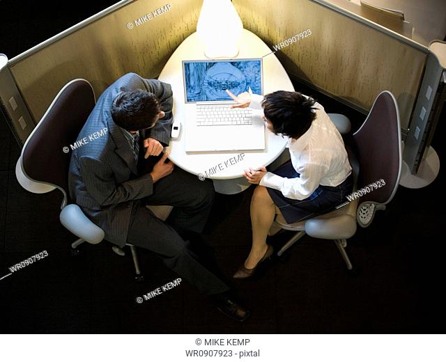 High angle view of a businesswoman and a businessman looking at a laptop