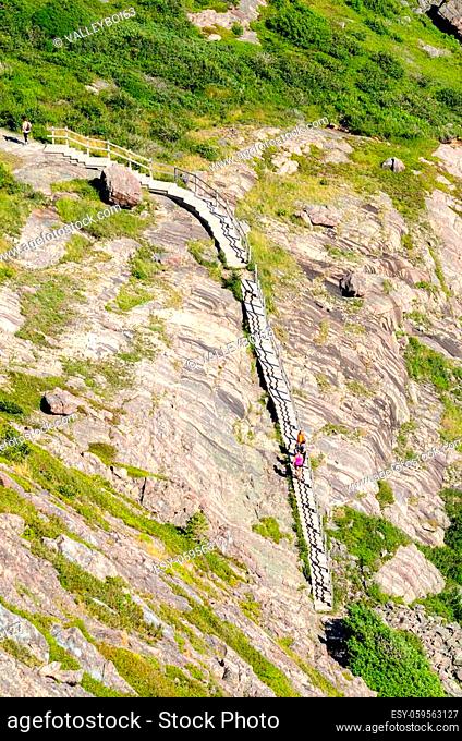 View of the Cabot Trail with hikers staying in shape, walking along in St John's, Newfoundland Canada steps rise and more rise on the granite crust of mother...