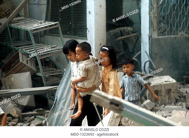A woman fleeing from the ruins of Saigon with her family. After the bombardment a Vietnamese woman flees from the tormented city with her three children