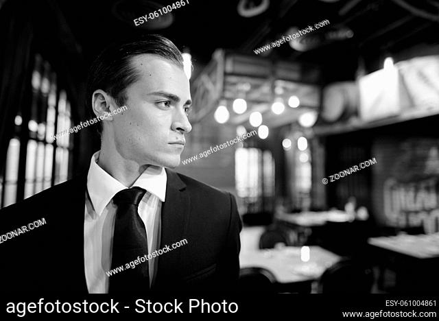 Portrait of young handsome businessman in suit exploring the city of Bangkok in black and white