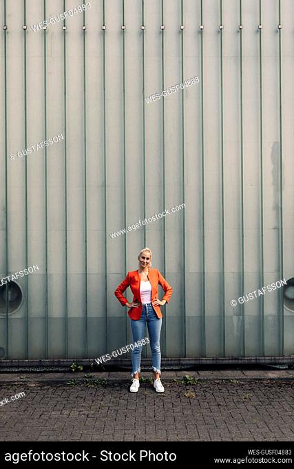 Female entrepreneur with hand on hip against wall