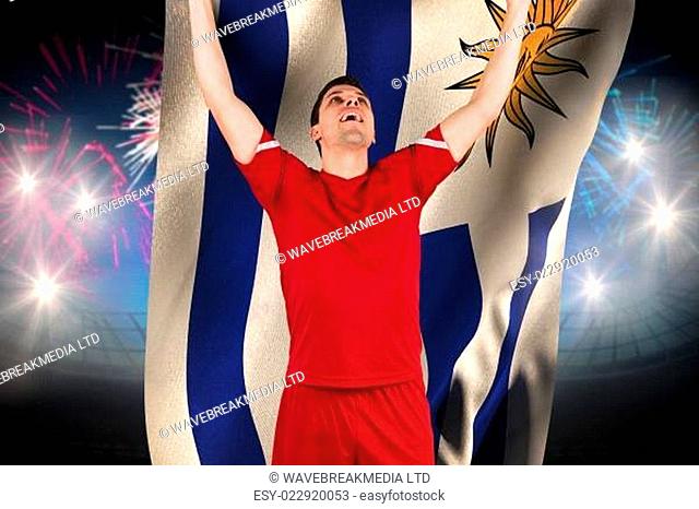 Excited football player cheering against fireworks exploding over football stadium and uruguay flag