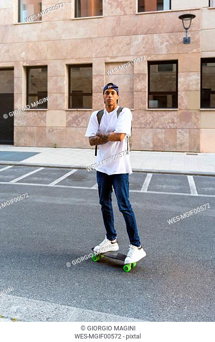 Portrait of tattooed young man standing on skateboard