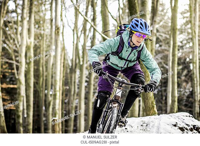 Female mountain biker riding through forest