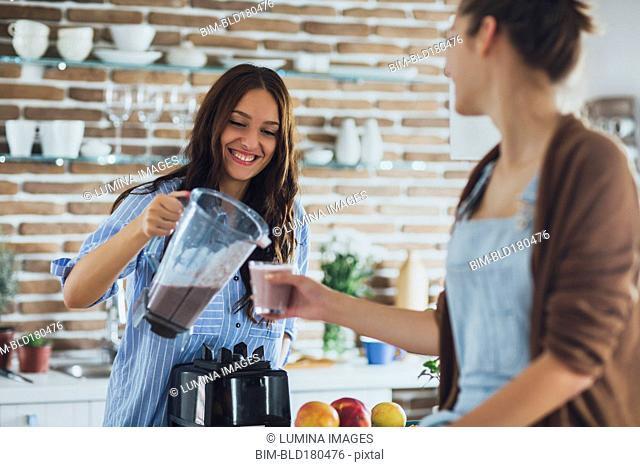 Caucasian women pouring smoothie in kitchen