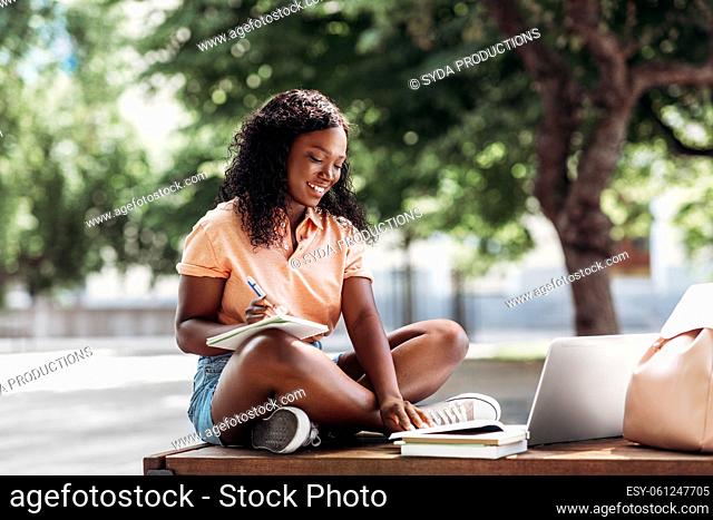 african student girl with laptop and books in city