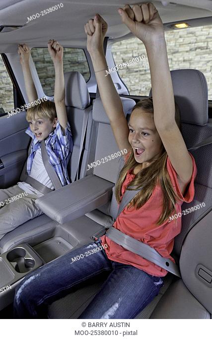 Cheerful children sitting at the back seat of car