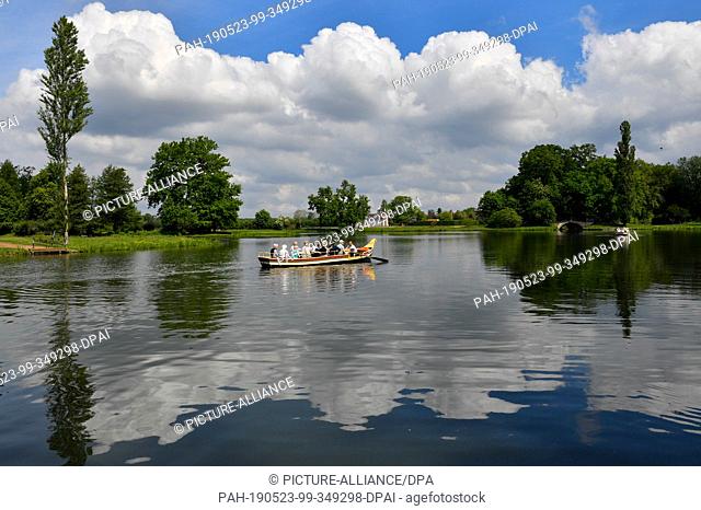 21 May 2019, Saxony-Anhalt, Oranienbaum-Wörlitz: A gondola with tourists drives along the world-famous Wörlitzer Park in front of the Palm House