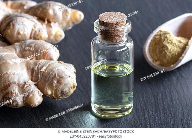 A bottle of essential oil with ginger root and powder