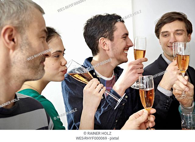 Germany, Cologne, Men and women toasting with champagne in office